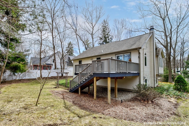 rear view of house featuring stairs, a chimney, a wooden deck, fence, and a lawn