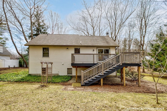 back of property featuring stairs, a chimney, a deck, roof with shingles, and a lawn