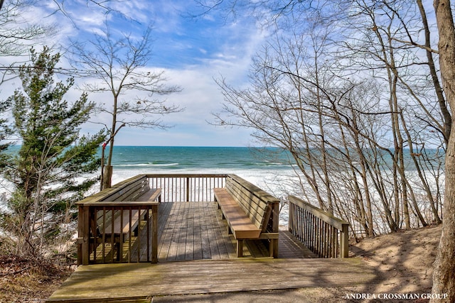 view of community with a deck with water view and a beach view