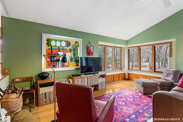 living room featuring lofted ceiling, light wood-style flooring, and a ceiling fan