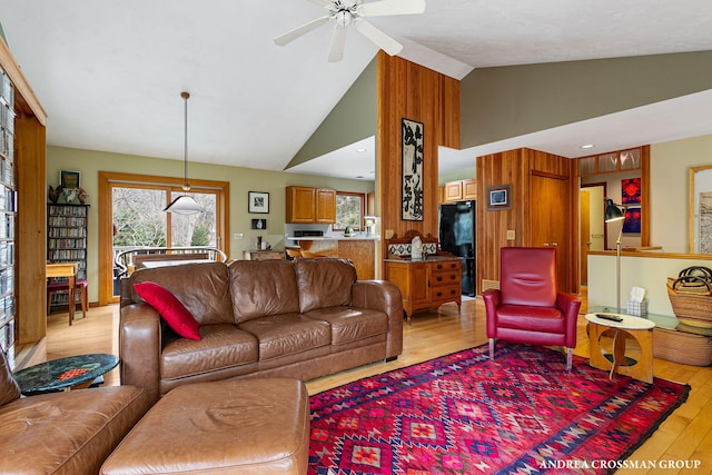living area featuring light wood finished floors, a wealth of natural light, high vaulted ceiling, and a ceiling fan