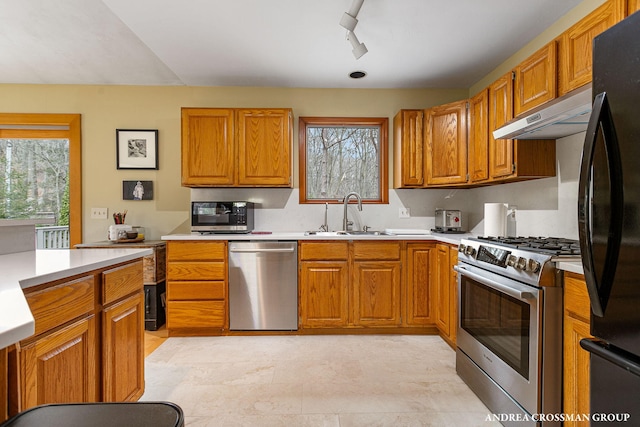 kitchen featuring a sink, a wealth of natural light, under cabinet range hood, and appliances with stainless steel finishes