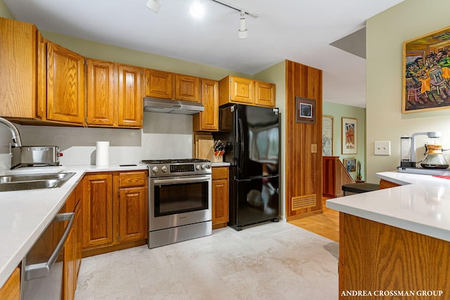 kitchen with light countertops, brown cabinets, stainless steel appliances, under cabinet range hood, and a sink