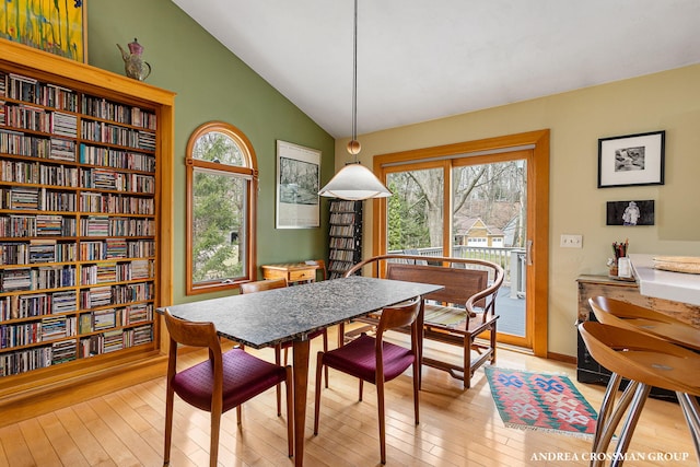 dining room with baseboards, lofted ceiling, and light wood-style flooring