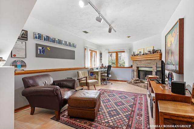 living room featuring a textured ceiling, a fireplace, visible vents, and tile patterned flooring