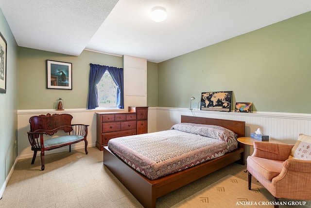 bedroom featuring a textured ceiling, carpet, and wainscoting