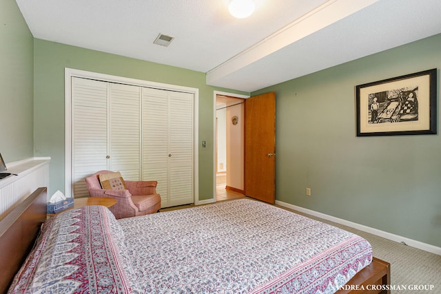 bedroom with a closet, visible vents, carpet flooring, and baseboards