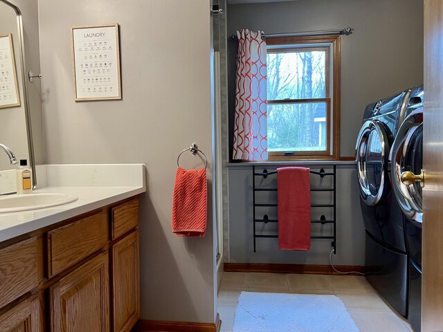 clothes washing area featuring light tile patterned flooring, washer and clothes dryer, laundry area, and a sink