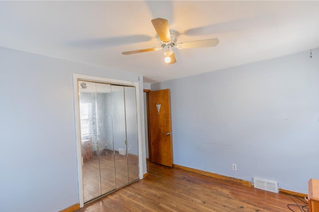 unfurnished bedroom featuring a closet, visible vents, baseboards, wood finished floors, and a ceiling fan