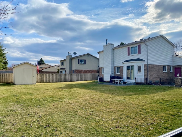 rear view of property with brick siding, a lawn, a fenced backyard, and a storage shed