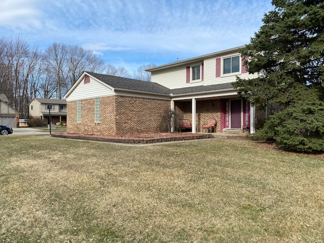 view of front of property featuring a front lawn, brick siding, and roof with shingles