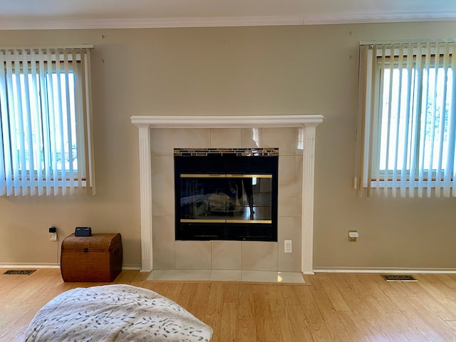 living room with a tile fireplace, wood finished floors, and visible vents