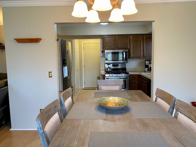 dining room featuring a chandelier, light wood finished floors, and ornamental molding
