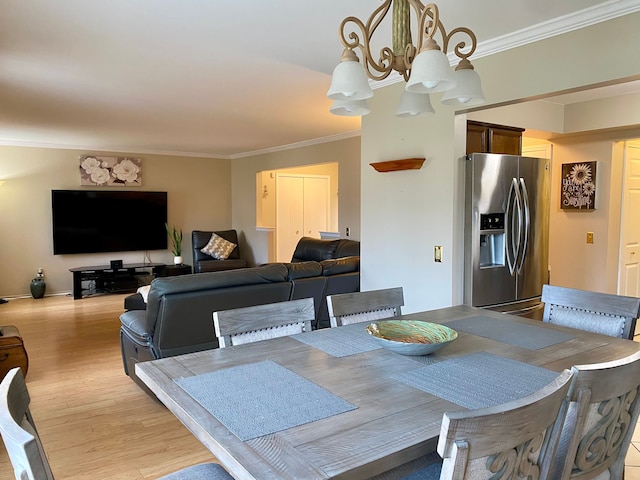 dining room with ornamental molding, a chandelier, and light wood-style flooring