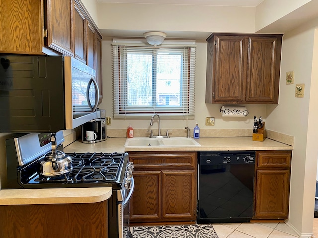 kitchen with light countertops, dishwasher, a sink, light tile patterned flooring, and stainless steel gas range