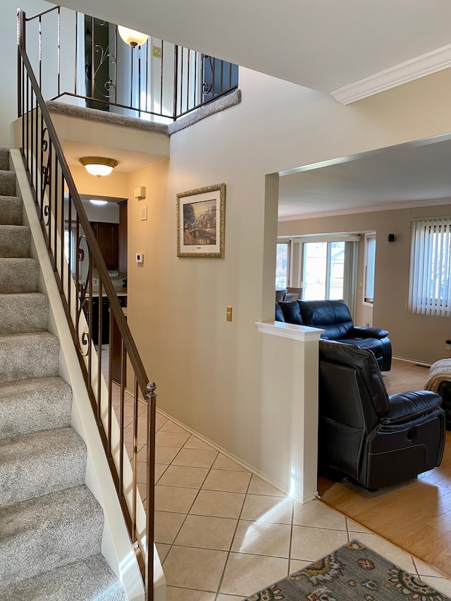 stairs with baseboards, crown molding, and tile patterned flooring