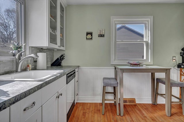 3034 Wolcott St, Ferndale, MI 48220 - kitchen featuring glass insert cabinets, a sink, light wood-type flooring, dishwashing machine, and a wainscoted wall