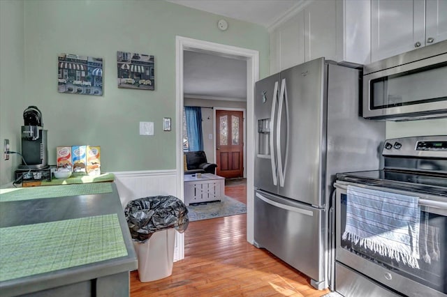 3034 Wolcott St, Ferndale, MI 48220 - kitchen featuring light wood-style floors, crown molding, white cabinetry, a wainscoted wall, and stainless steel appliances