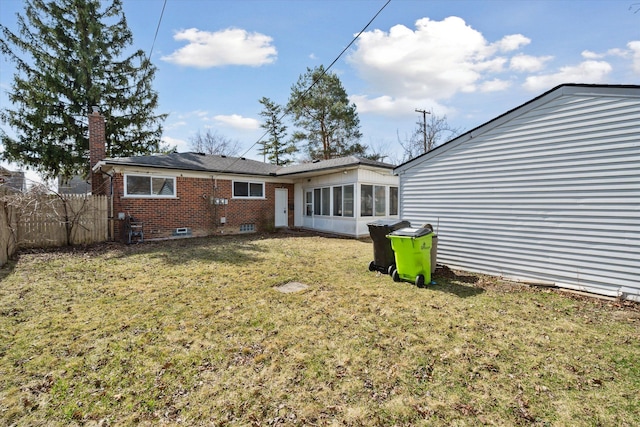 back of property featuring a yard, brick siding, fence, and a chimney