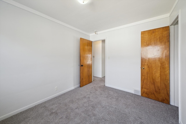 unfurnished bedroom featuring crown molding, visible vents, baseboards, and carpet