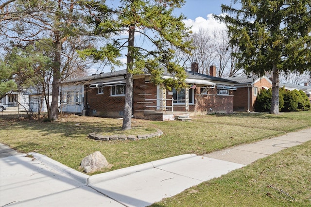 ranch-style home featuring brick siding, a chimney, and a front lawn