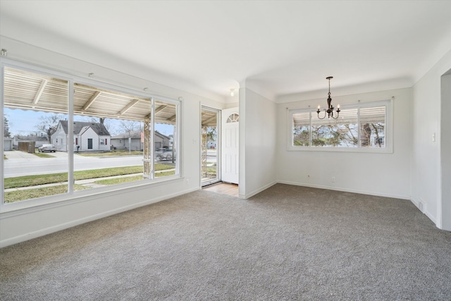 empty room with baseboards, carpet flooring, and a notable chandelier