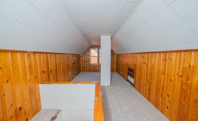 additional living space with lofted ceiling, wooden walls, and carpet flooring