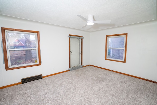 unfurnished room with visible vents, a ceiling fan, carpet flooring, and baseboards
