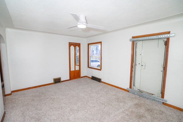unfurnished room with arched walkways, ceiling fan, carpet flooring, baseboards, and visible vents