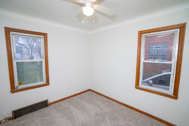 carpeted empty room featuring visible vents, a ceiling fan, and baseboards
