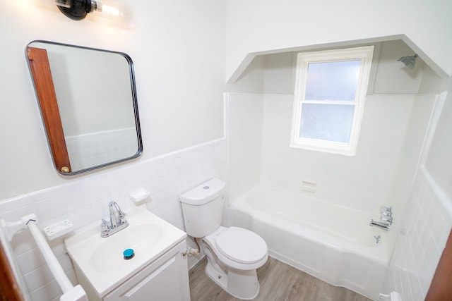 full bathroom with wood finished floors, wainscoting, tile walls, toilet, and vanity