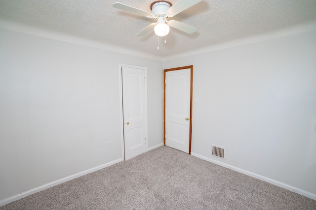 carpeted empty room with a textured ceiling, visible vents, ceiling fan, and baseboards