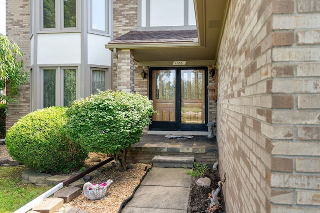 property entrance with brick siding, stucco siding, and french doors