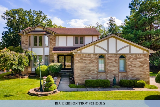 tudor-style house with stucco siding, brick siding, and a front yard