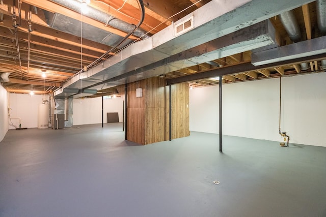 unfinished basement with visible vents, heating unit, and gas water heater