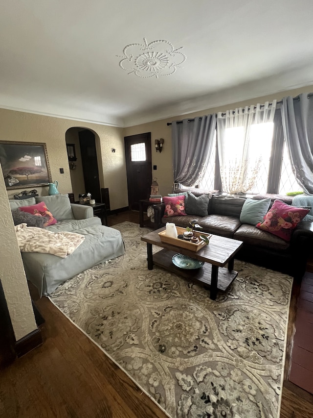 living room featuring arched walkways, ornamental molding, and wood finished floors