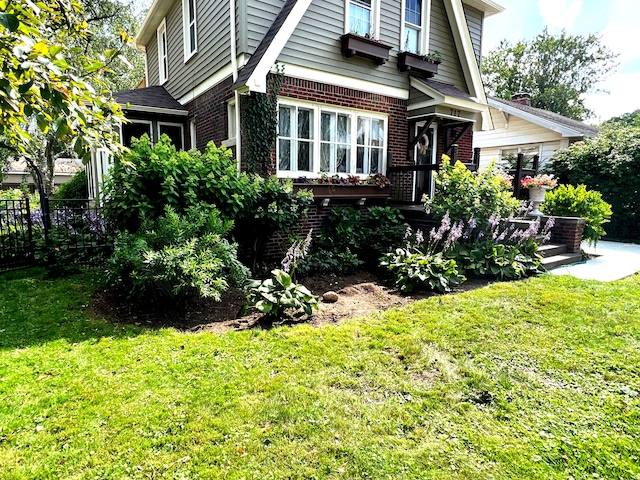 view of side of property with brick siding, fence, and a yard