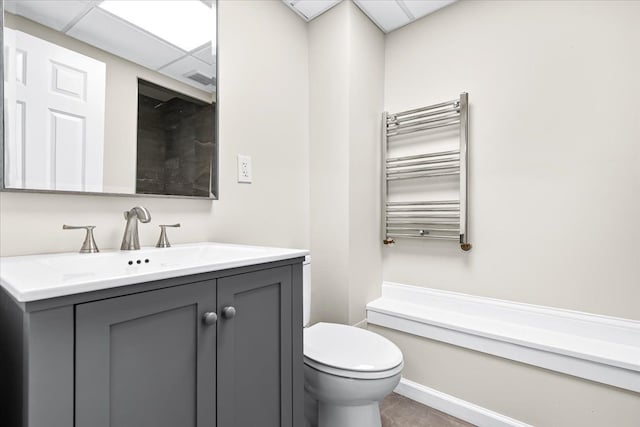 423 Heights Rd, Lake Orion, MI 48362 - bathroom with radiator heating unit, toilet, vanity, a towel warming rack, and a paneled ceiling