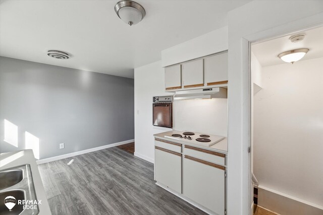 3738 Holly Ave, Flint, MI 48506 - kitchen featuring white electric stovetop, under cabinet range hood, dark wood-style floors, light countertops, and oven