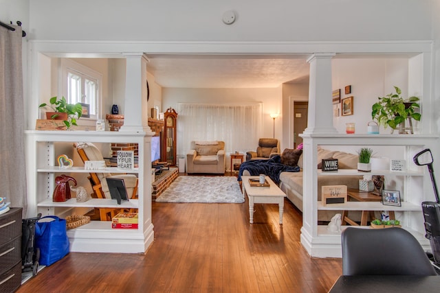 living area featuring hardwood / wood-style floors and decorative columns