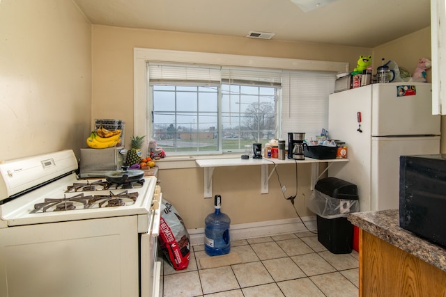 kitchen featuring visible vents, baseboards, white appliances, and light tile patterned floors