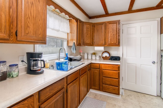 kitchen with brown cabinetry, a sink, and light countertops