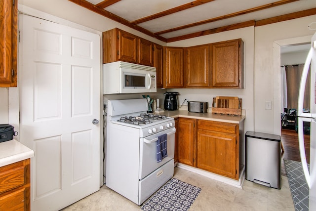 kitchen with brown cabinetry, light countertops, and white appliances