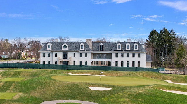 view of home's community with a putting green, view of golf course, and fence