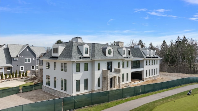 view of front of property featuring stucco siding, a fenced backyard, and a chimney
