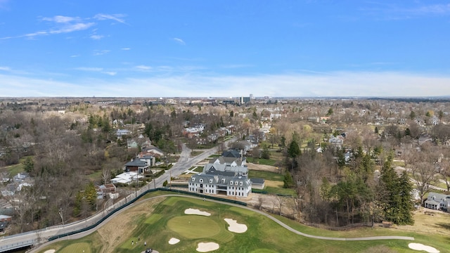 aerial view of property and surrounding area featuring a golf course, a tree filled landscape, and nearby suburban area