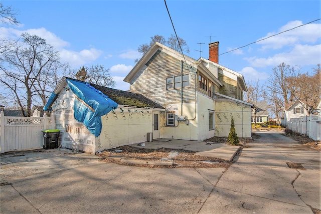 215 W Grove St, Greenville, MI 48838 - rear view of house with a chimney, fence, and concrete driveway