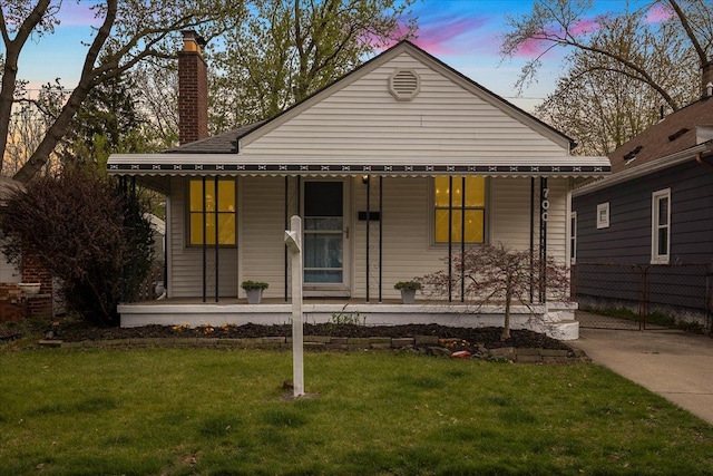 bungalow featuring a chimney, a porch, and a front yard