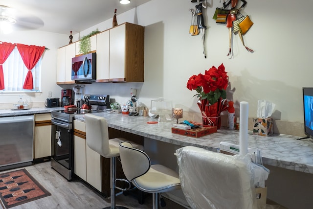 kitchen with light wood-type flooring, light countertops, and appliances with stainless steel finishes