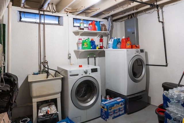 laundry room with electric panel, washing machine and clothes dryer, laundry area, and a sink